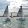 A fleet of small 2 person sailboats cutting through the open waters of a bay